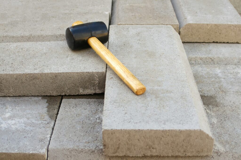 paving hammer. Stack of paving stones. Garden brick pathway paving by professional paver worker. Lay